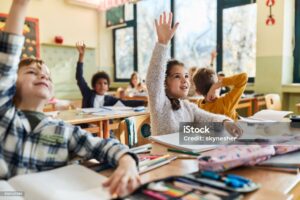 Children raising their hands in a classroom to speak up and share their ideas